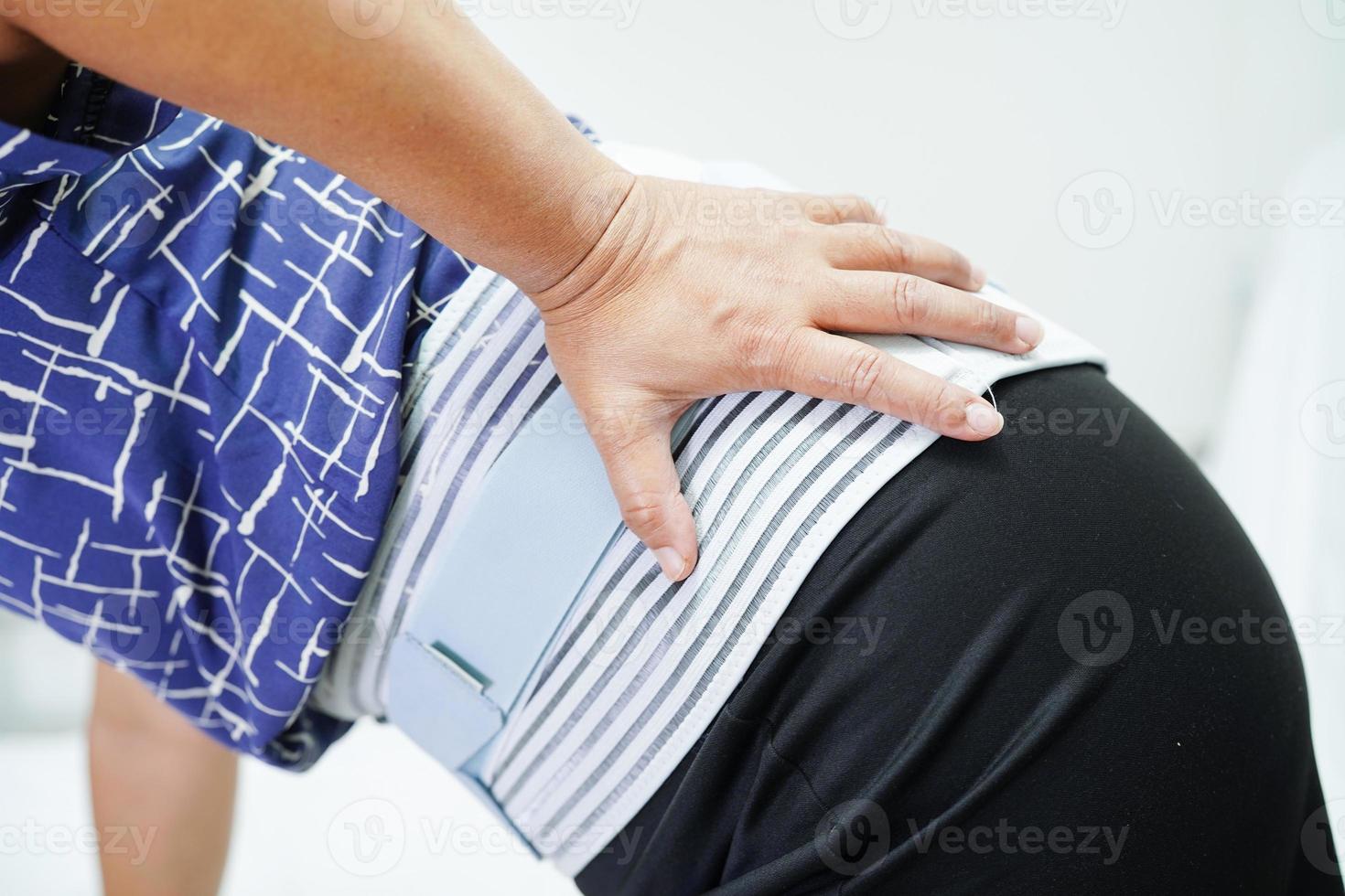 asiatisk senior som bär elastiskt stödbälte kan hjälpa till att minska ryggsmärtor. foto