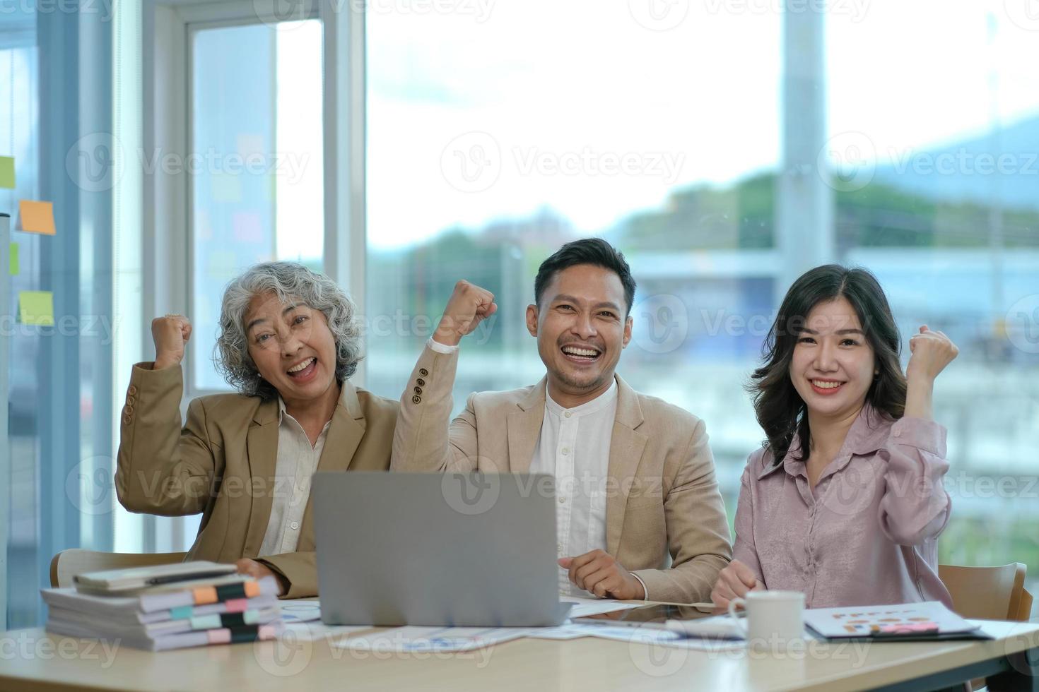 grupp av unga asiatiska affärsteam kreativa affärsmän medarbetare på kontoret glada över att vara framgångsrika partnerskap lagarbete firar prestation och framgång koncept. foto