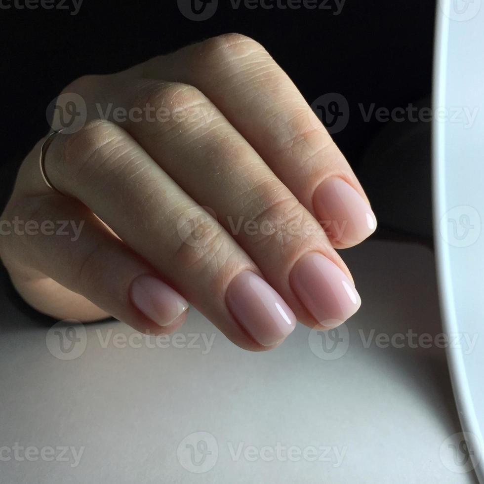 manikyr - vackert välskött kvinnas fingernaglar med trevlig rosa nagel putsa foto