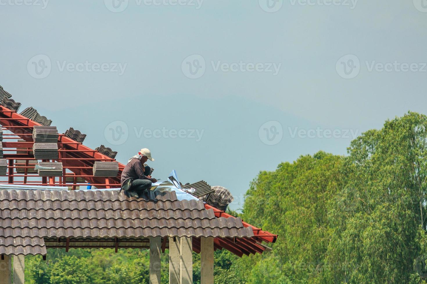 byggtäckare som installerar takpannor på husbyggarbetsplatsen foto