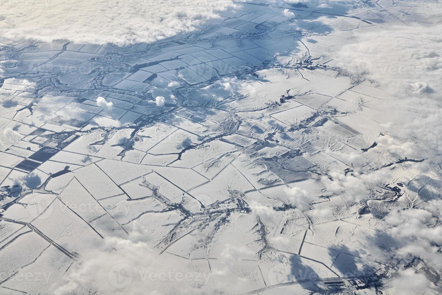 antenn clouds se över moln topp till snö täckt floder, vägar, städer och fält, vinter- luft foto