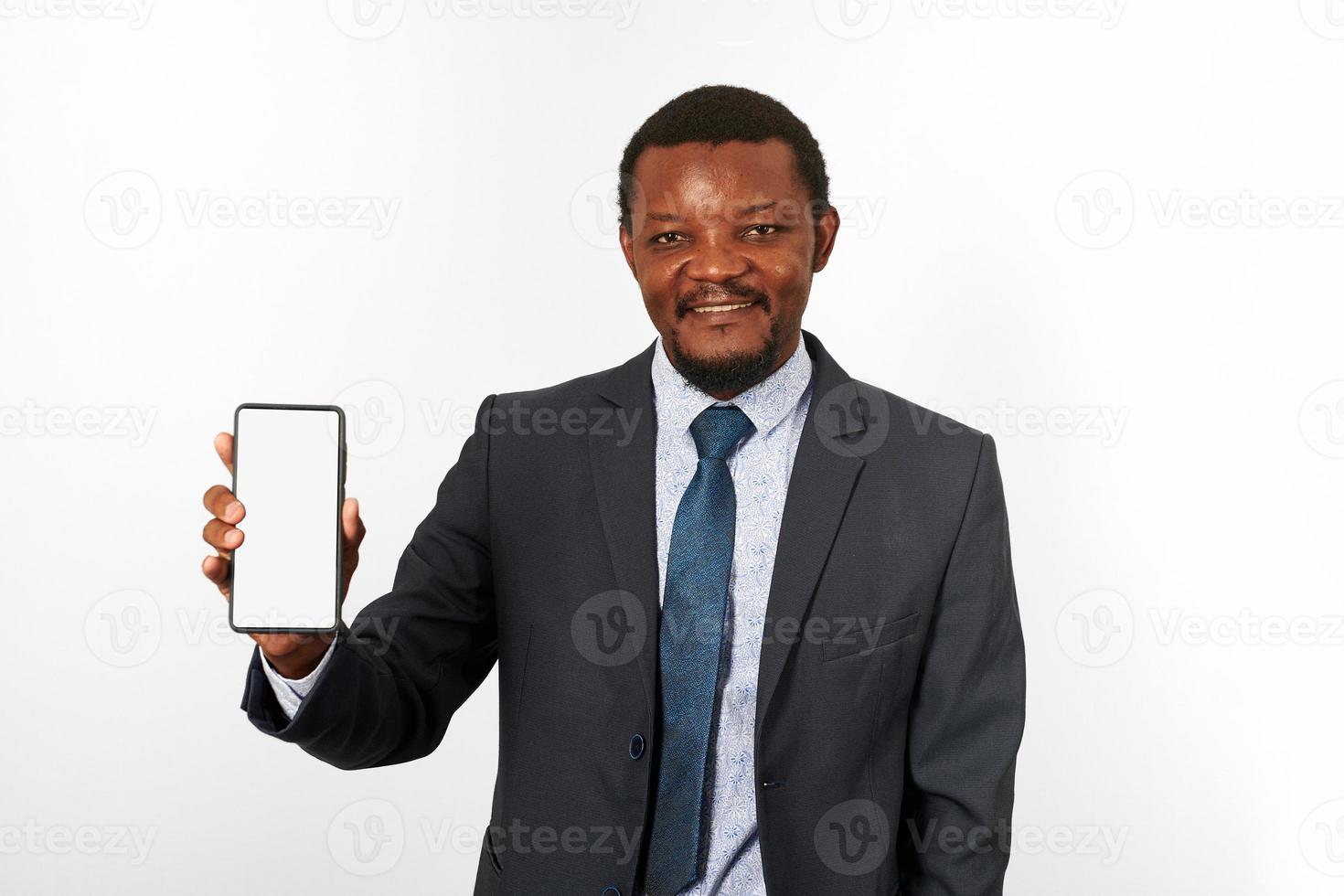 leende afrikansk amerikan svart man i företag kostym med smartphone attrapp i hand, vit bakgrund foto