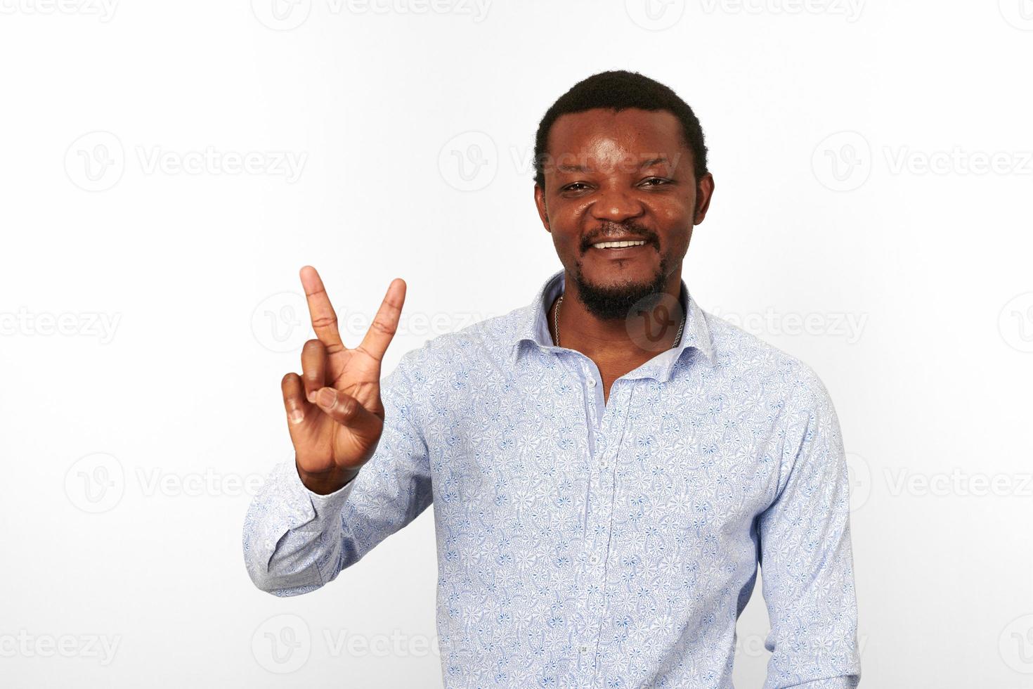 Lycklig afrikansk amerikan svart man med v tecken gest i tillfällig ljus skjorta vit bakgrund foto