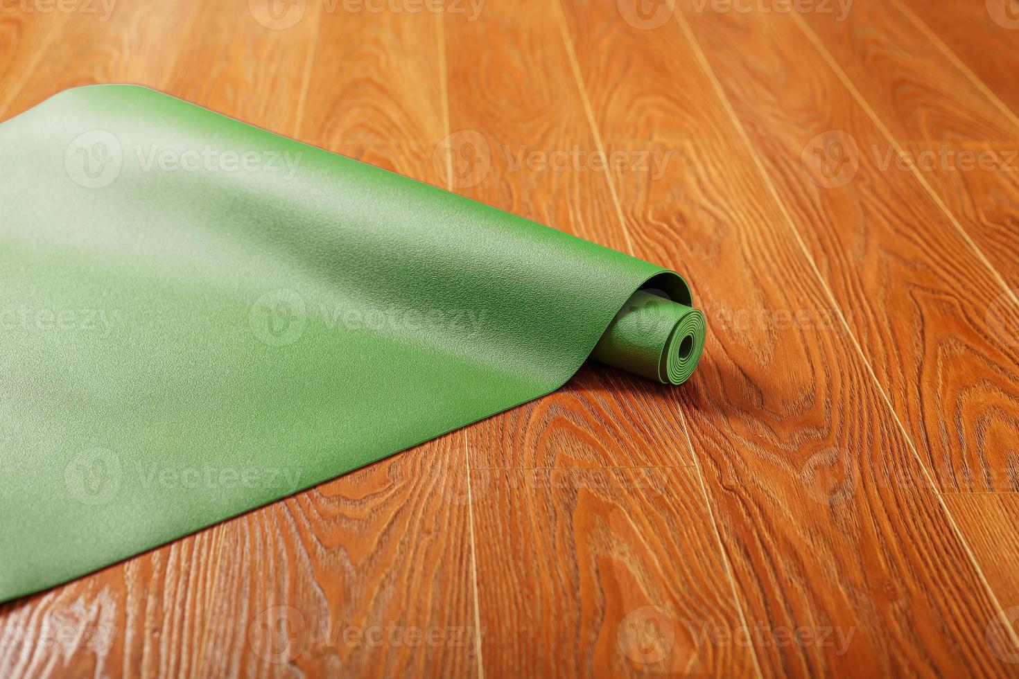 en grön yoga matta är lagd ut i en rulla på de trä- golv. foto
