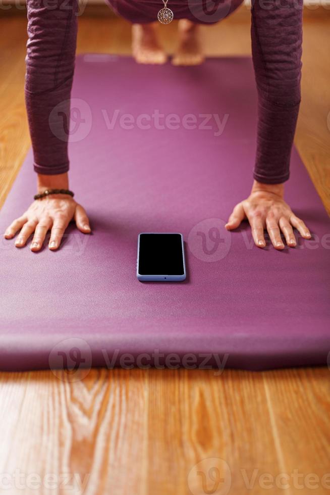 yoga uppkopplad Träning träna förbi smartphone, använder sig av de kondition app på Hem i de Gym. foto