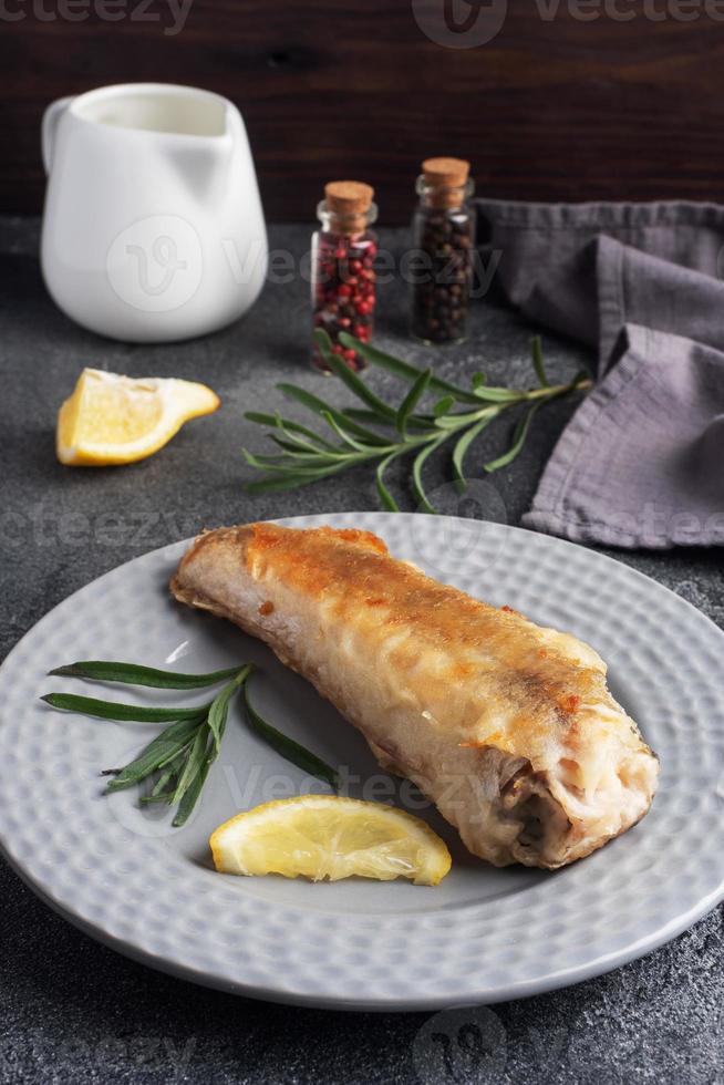 friterad fisk kummel pollock och skivor av färsk citron. mörk betong bakgrund. kopia Plats. foto