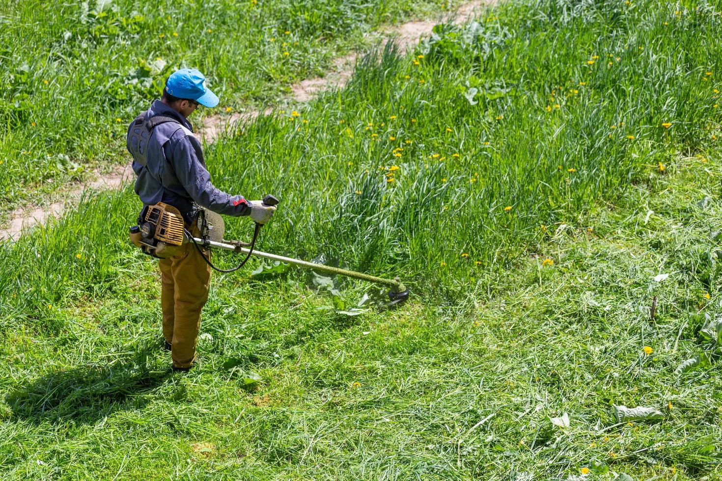 tula, ryssland Maj 19, 2020 ryska officiell gräsklippare arbetstagare man skärande grön gräs med två cykler motor sträng trimmer. topp till ner se. foto
