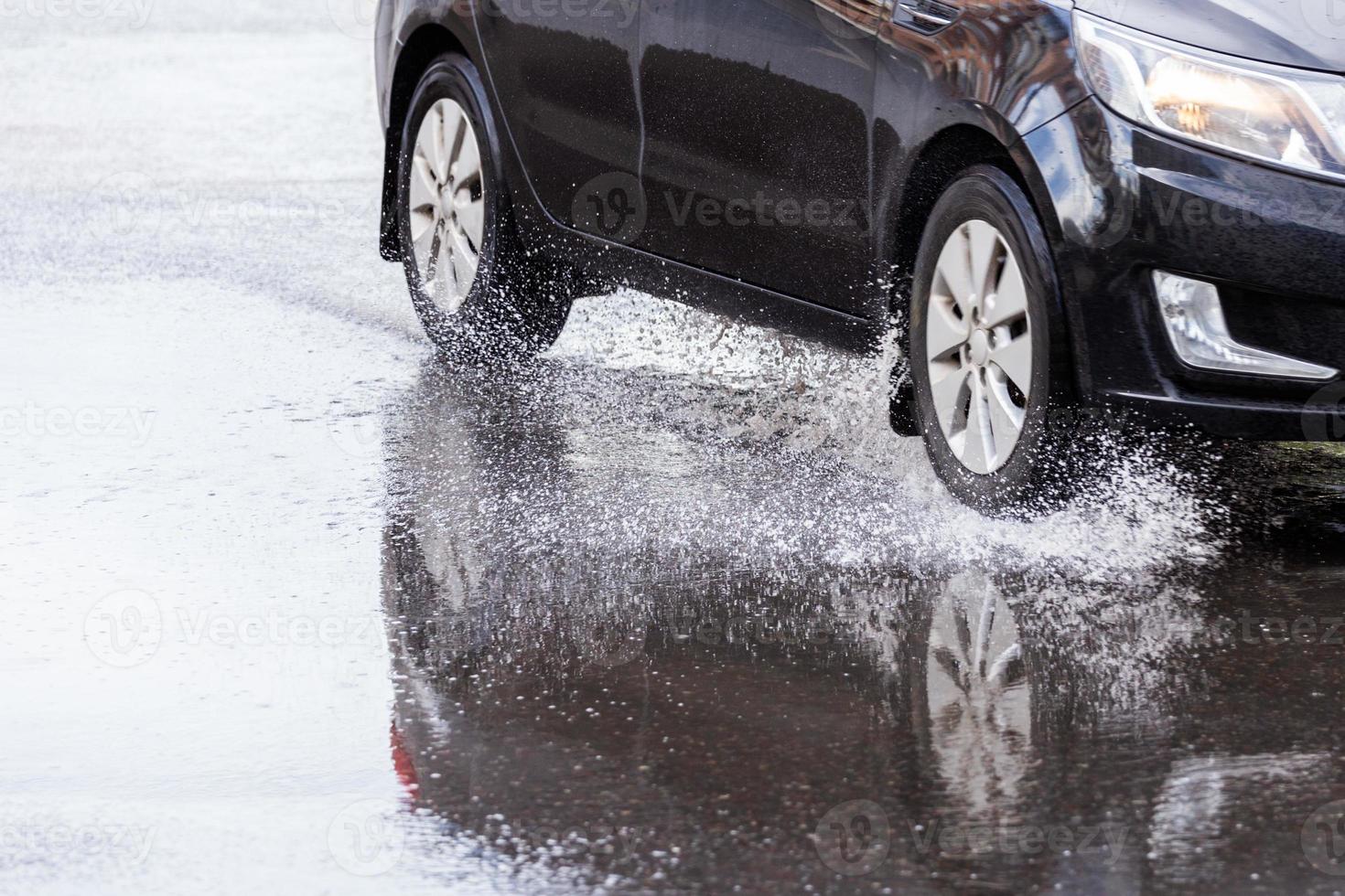svart bil korsning pöl med vatten stänk på dagsljus närbild foto