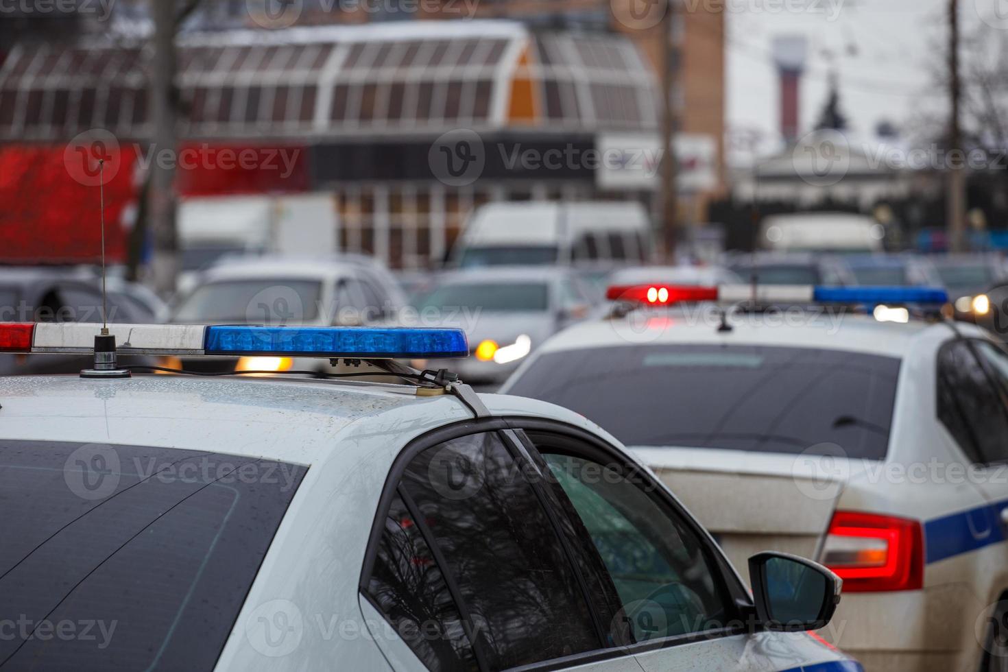 två polis bilar lampor i stad gata på vinter- dag med bilar trafik i suddigt bakgrund foto