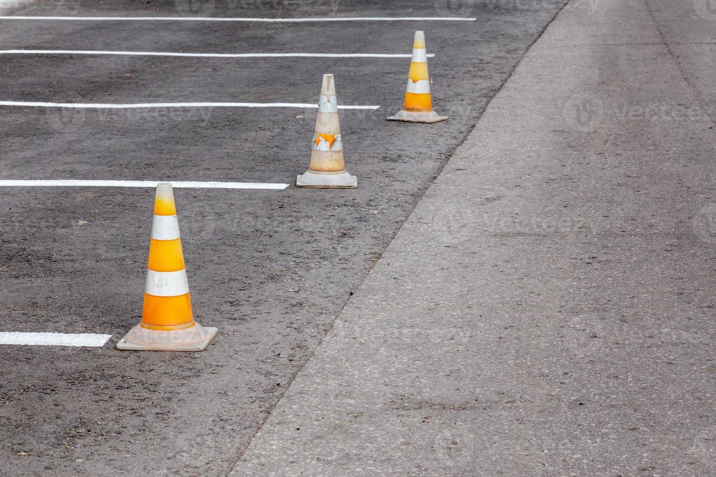 orange väg koner på en asfalt körning område med vit rader foto