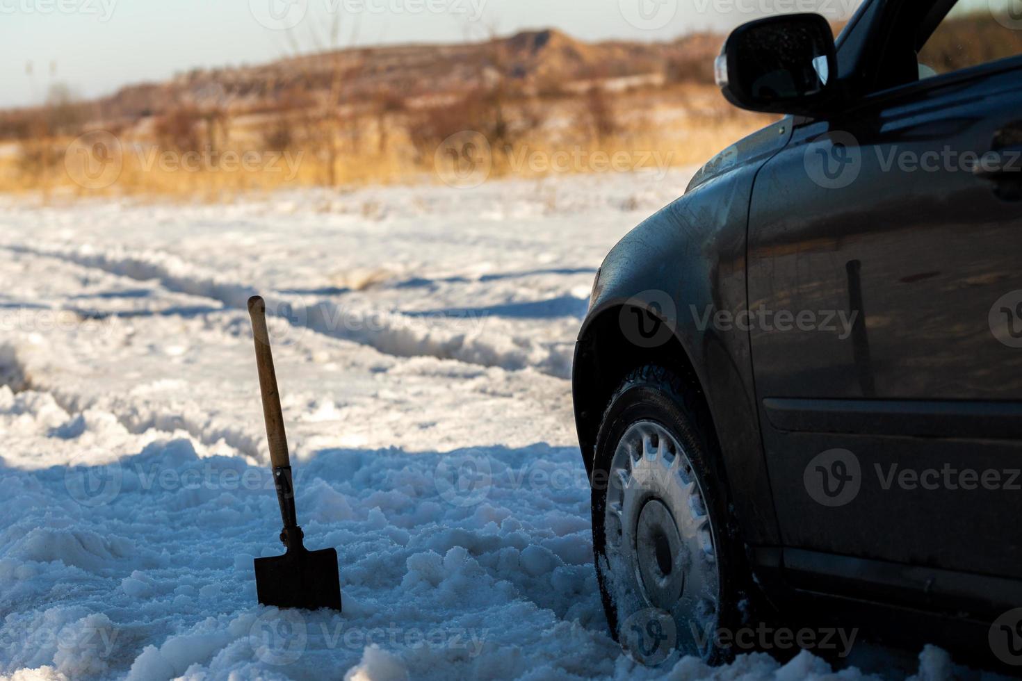 bil fastnat i snö av vägen på dagsljus med skyffel och selektiv fokus foto