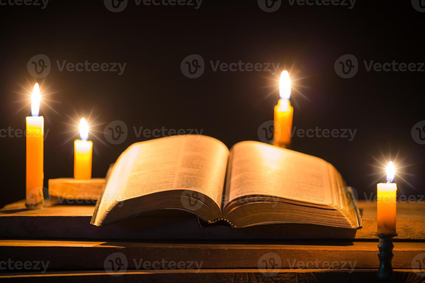 ljus ljus med helig bibel och korsa eller krucifix på gammal trä- bakgrund i kyrka.stearinljus och öppen bok på årgång trä tabell kristendomen studie och läsning i hem.koncept av christ religion foto