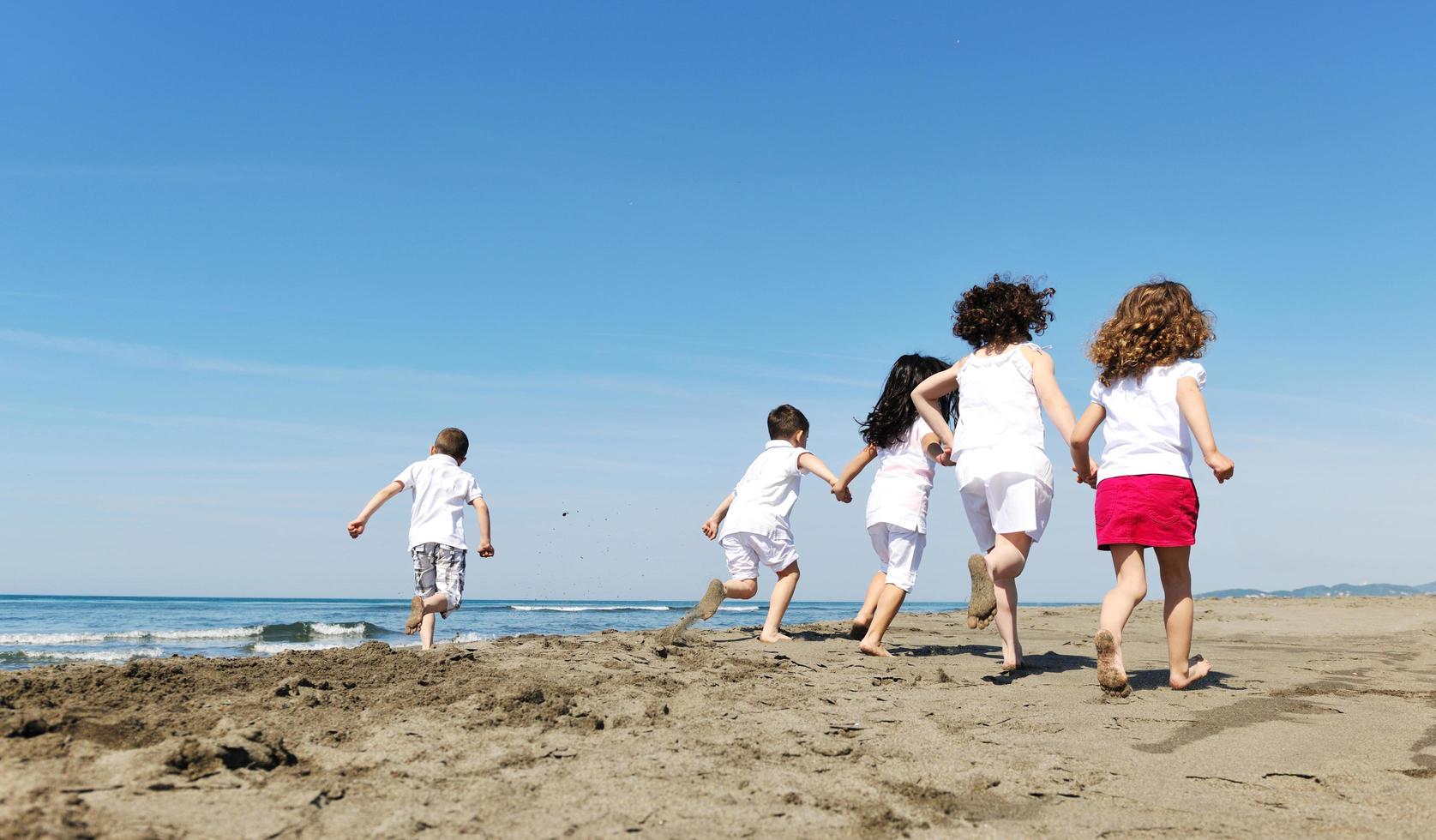 glad barn grupp som leker på stranden foto