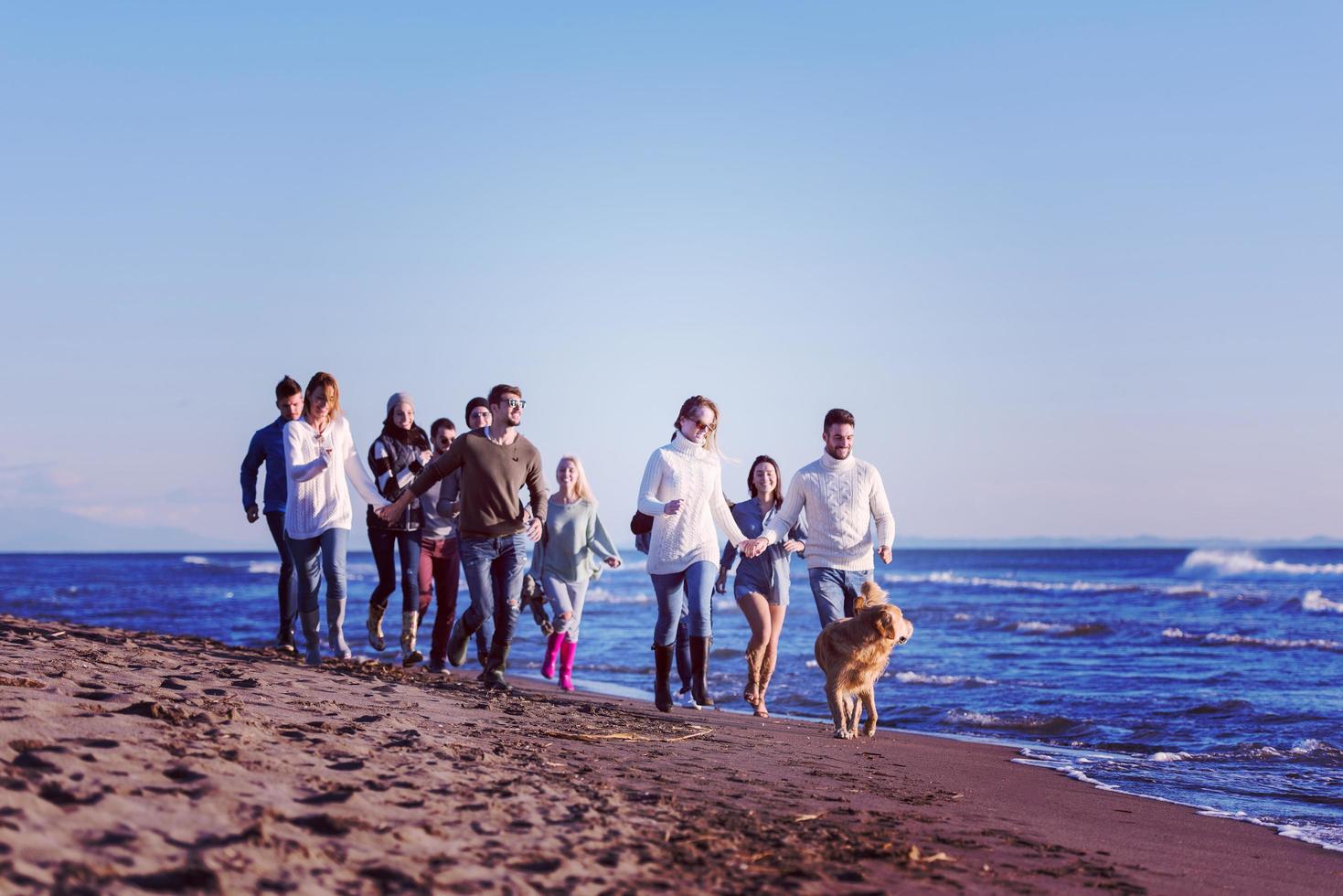 grupp av vänner löpning på strand under höst dag foto