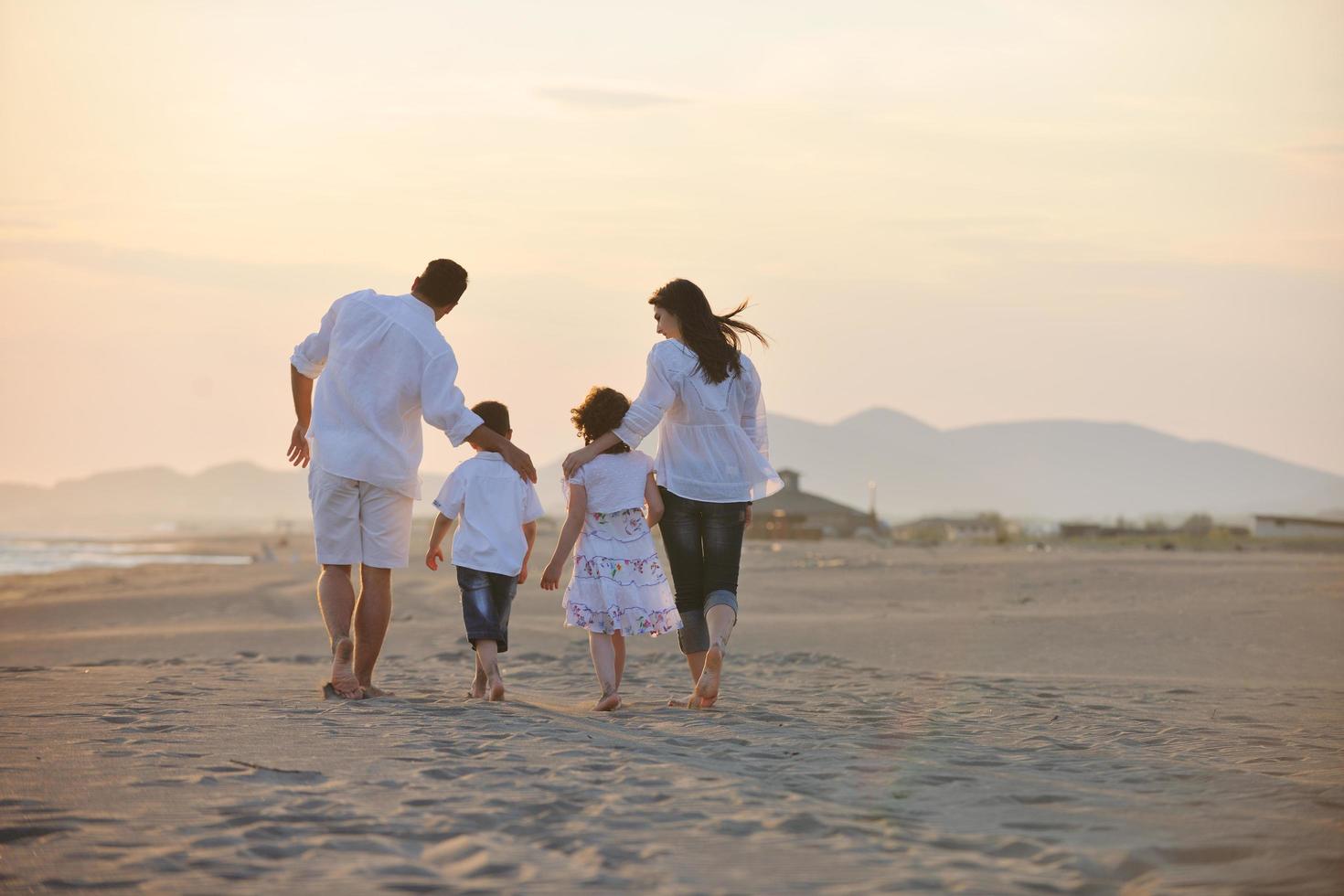 Lycklig ung familj ha roligt på strand på solnedgång foto