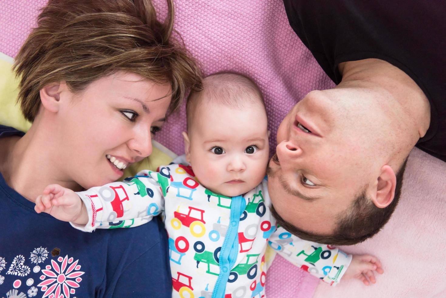 topp se av leende ung par liggande med deras bebis foto