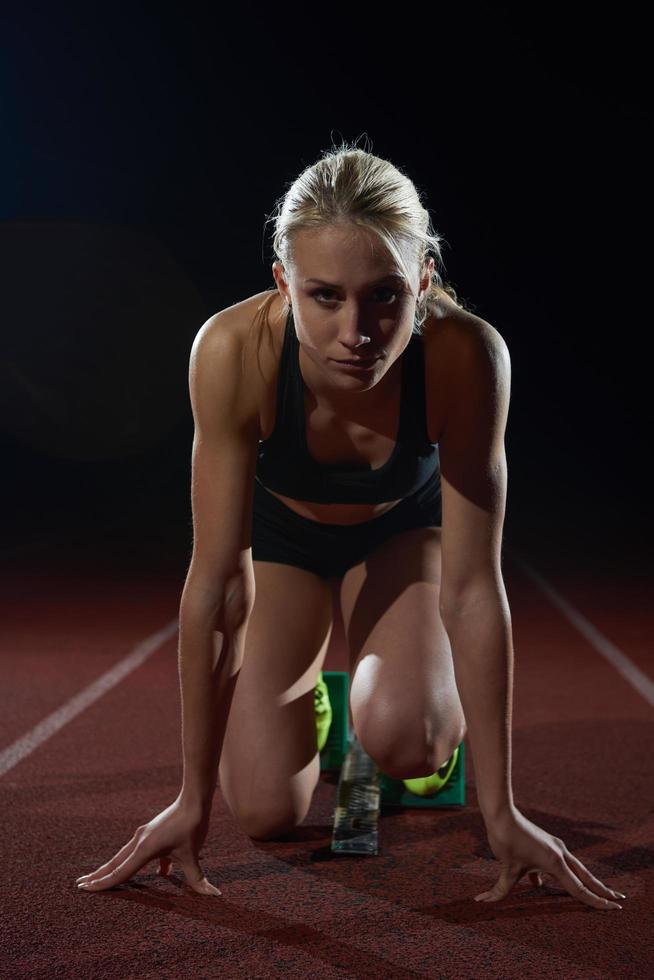 kvinna sprinter lämnar startande block foto