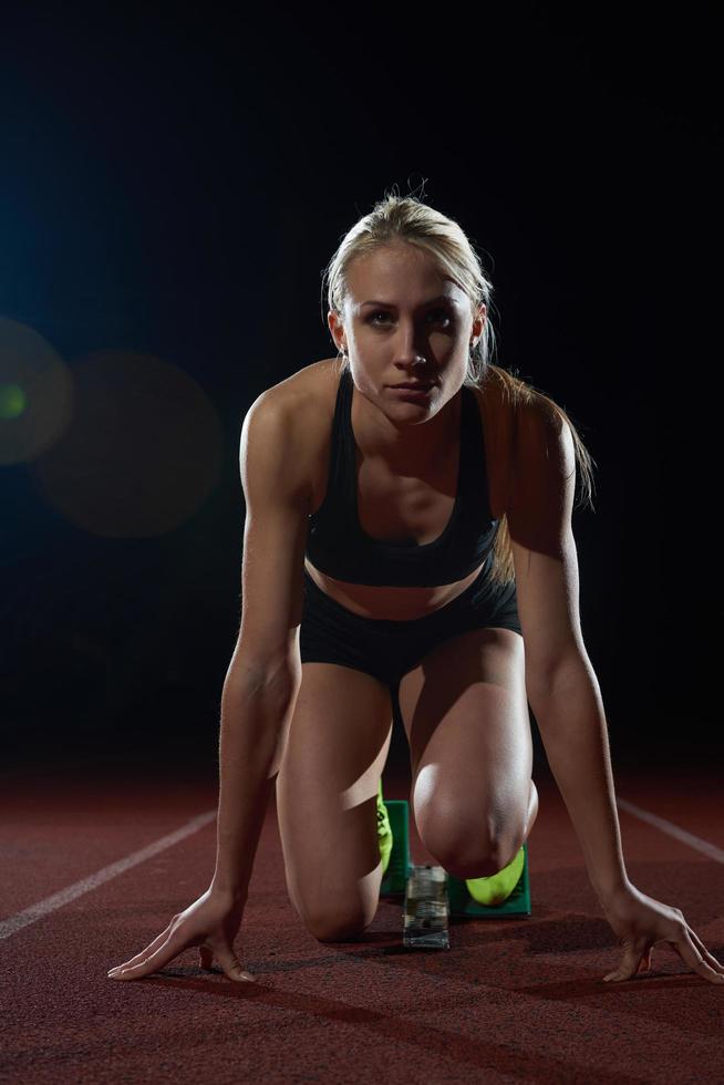 kvinna sprinter lämnar startande block foto