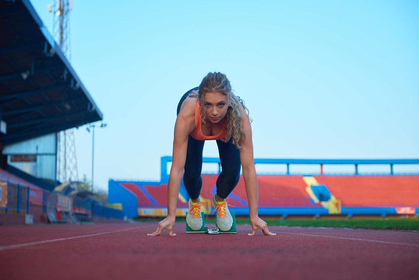 kvinna sprinter lämnar startande block foto