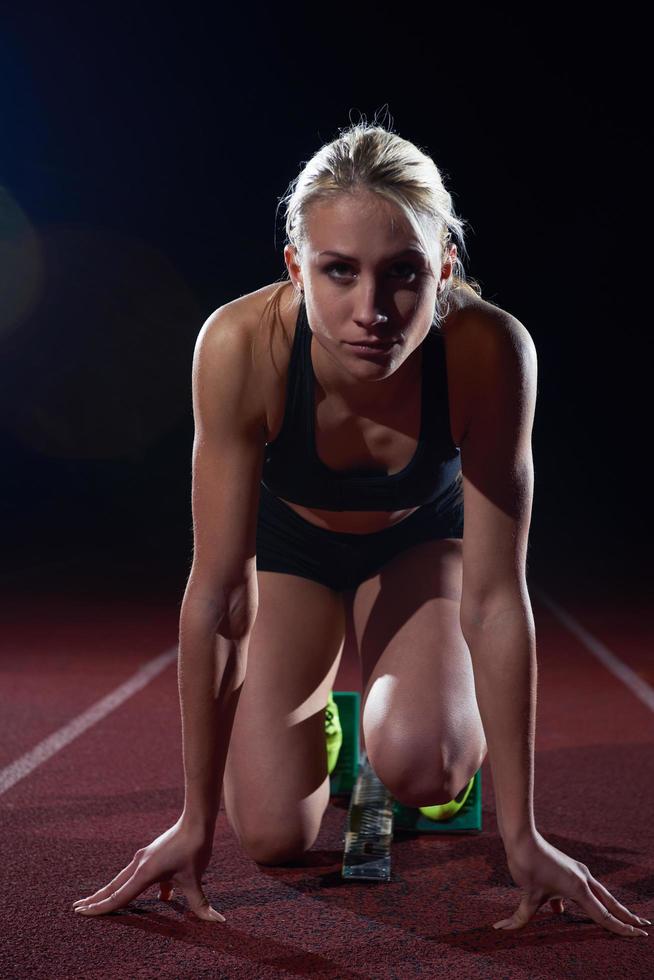 kvinna sprinter lämnar startande block foto