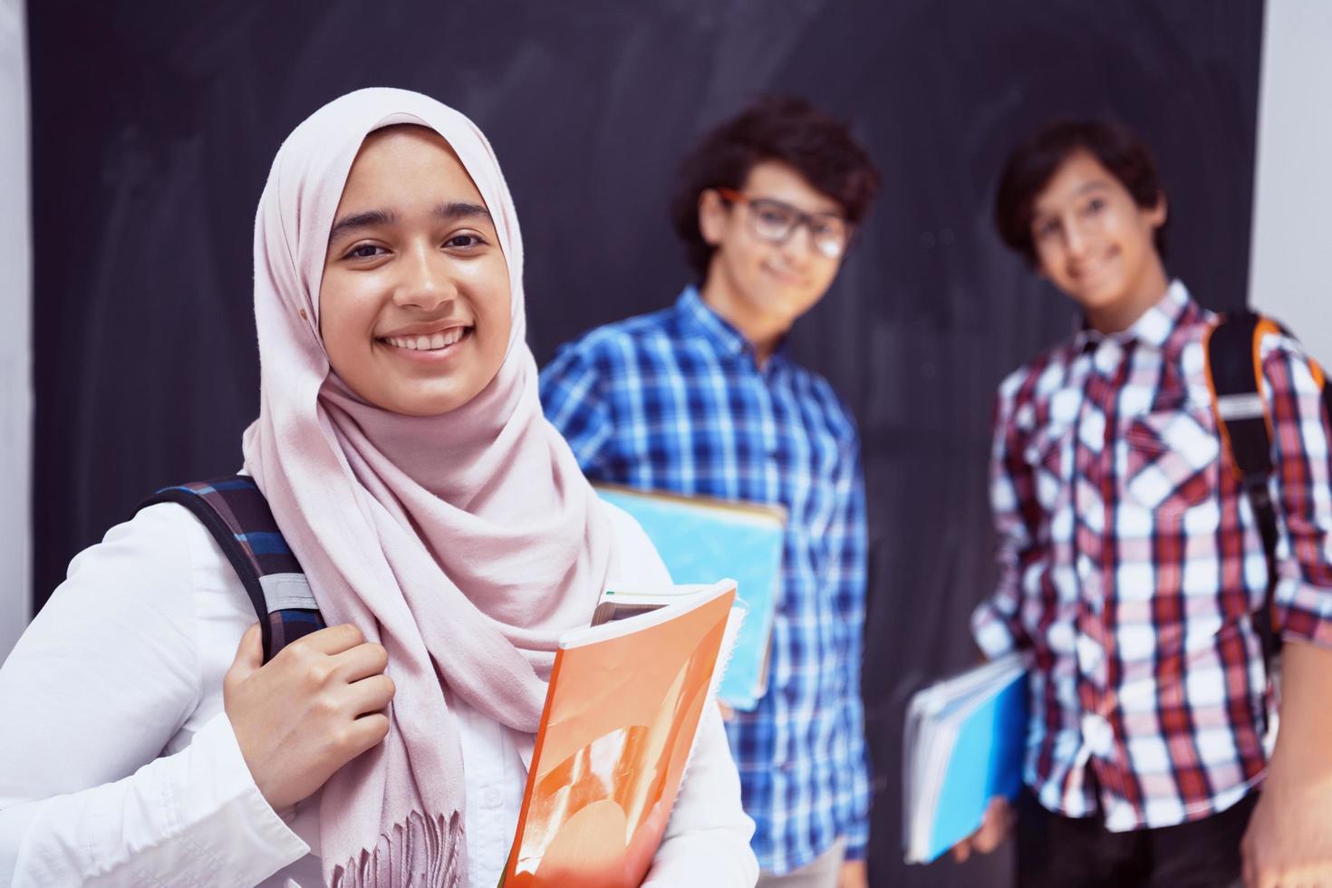 arabicum tonåringar, studenter grupp porträtt mot svart svarta tavlan bär ryggsäck och böcker i skola.selektiv fokus foto