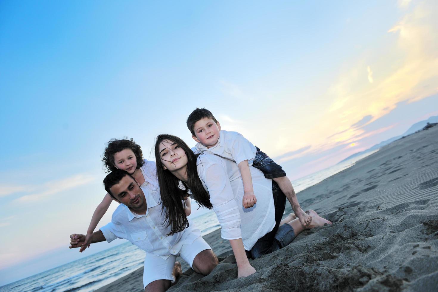 Lycklig ung familj ha roligt på strand foto