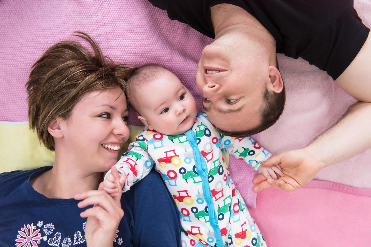 topp se av leende ung par liggande med deras bebis foto