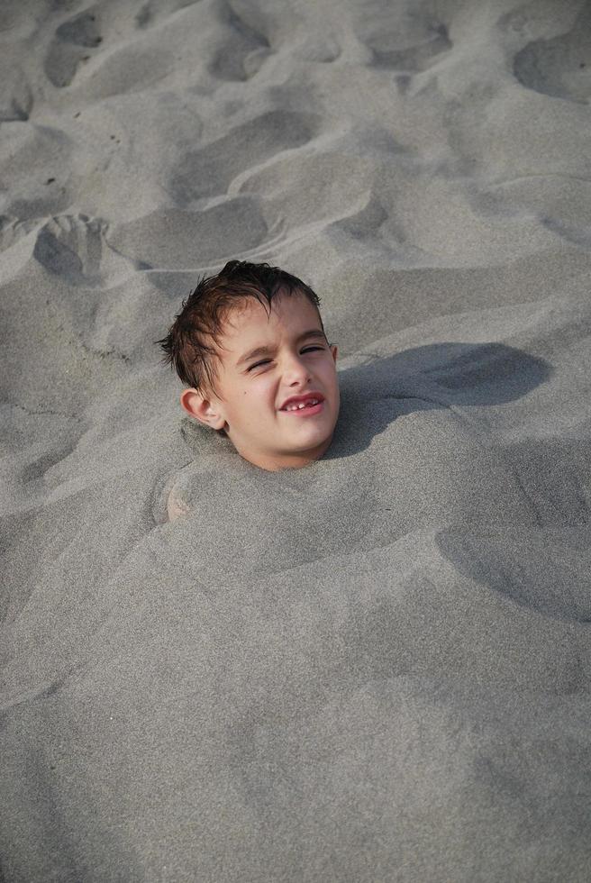 Lycklig barn begravd i sand foto