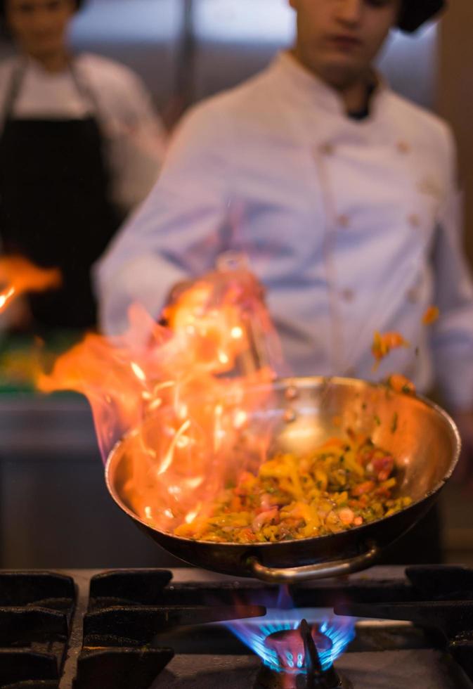 kock håller på med flambe på mat foto