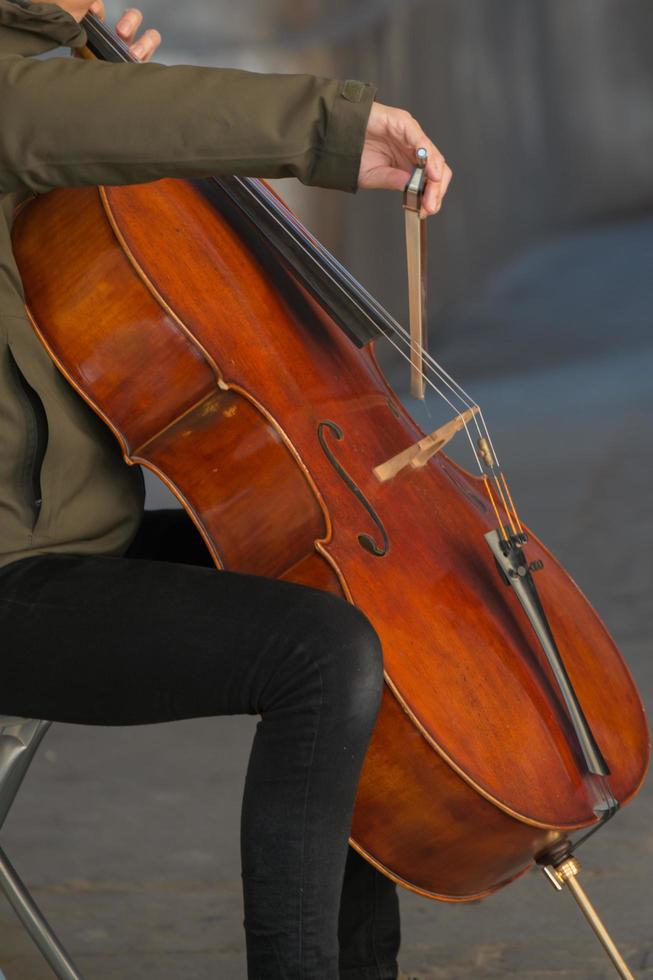 oigenkännlig person spelar cello på de gata foto