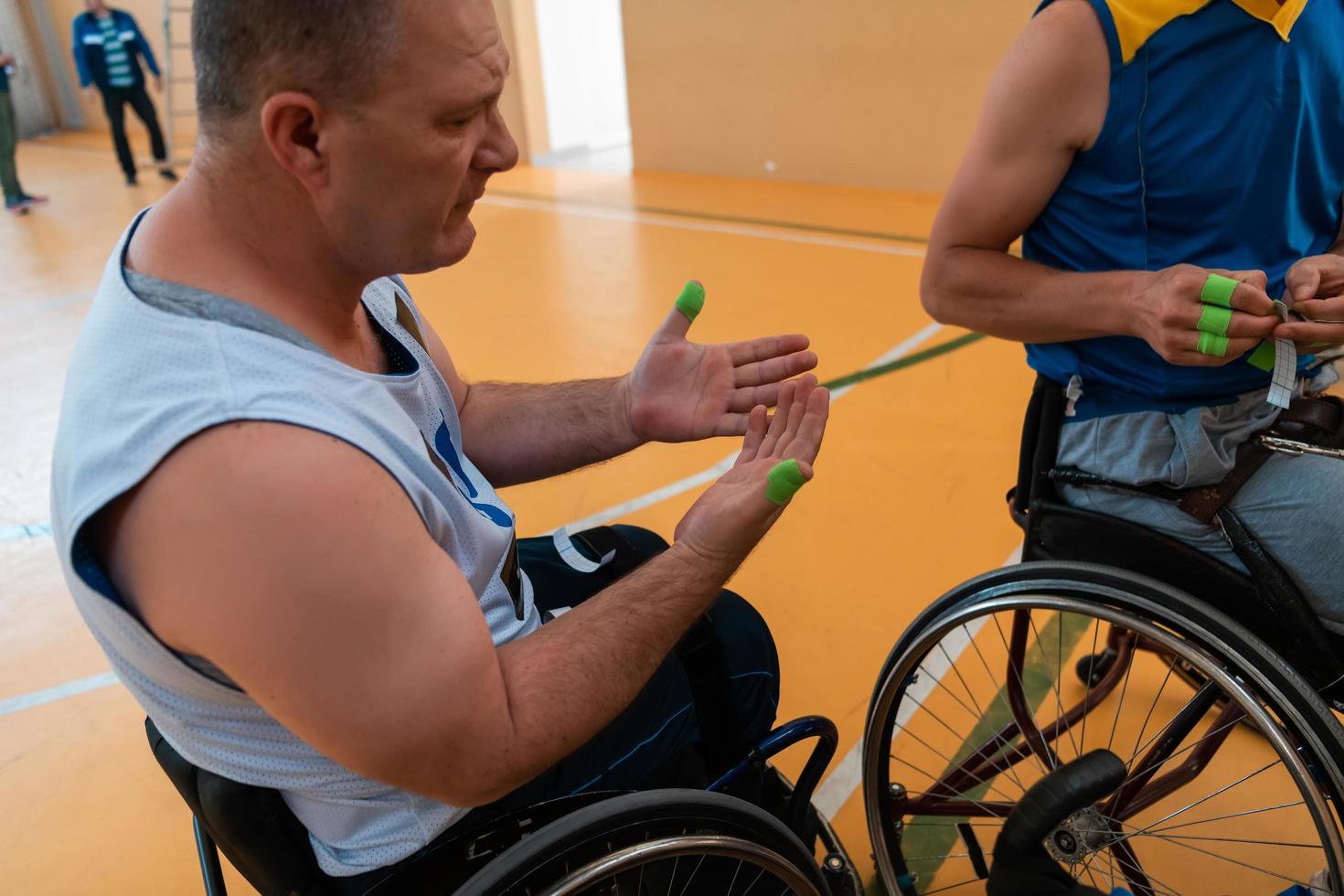 en Inaktiverad basketboll spelare sätter på en korsett och bandage på hans vapen och fingrar i förberedelse för en spel i de arena foto