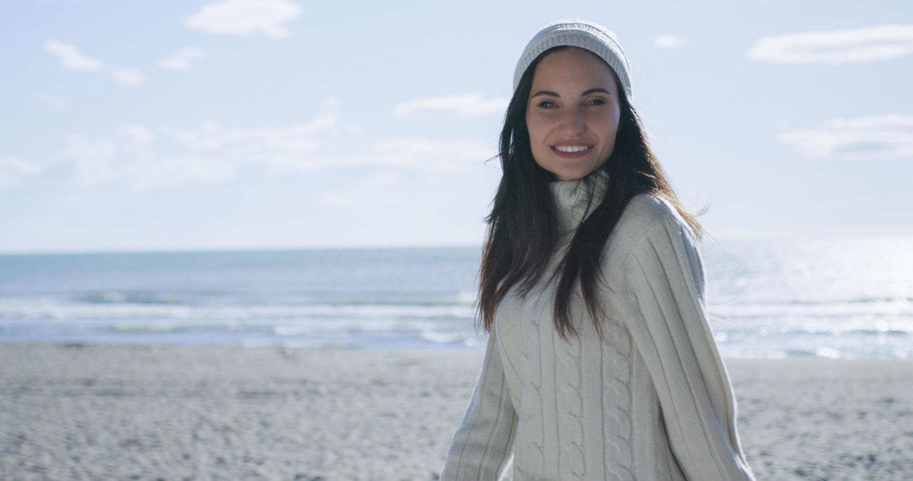 flicka i höst kläder leende på strand foto