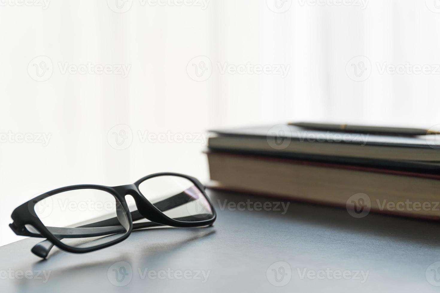 glasögon och bok på de skrivbord foto