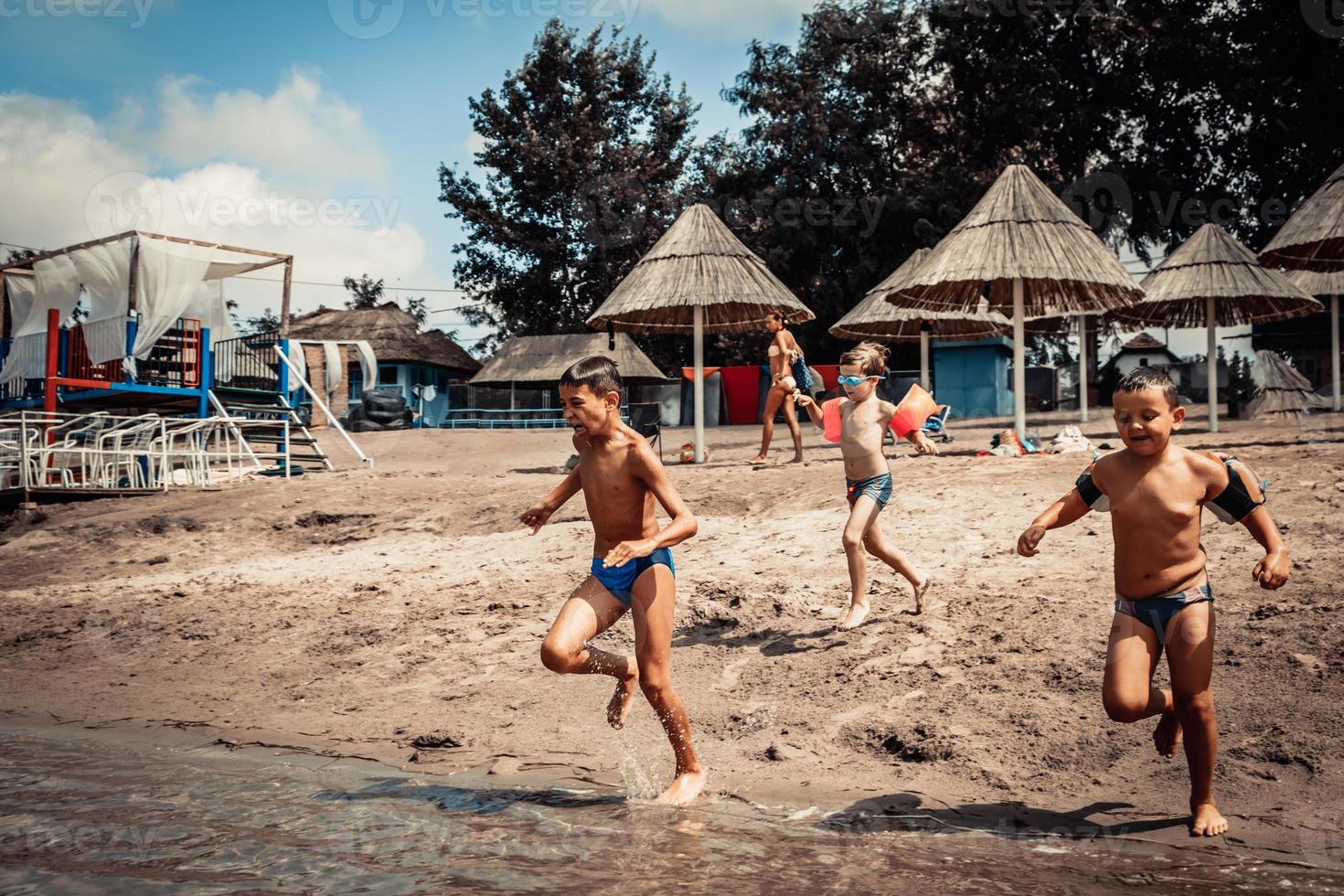 lekfull Pojkar har roligt medan löpning på de strand på sommar dag. foto