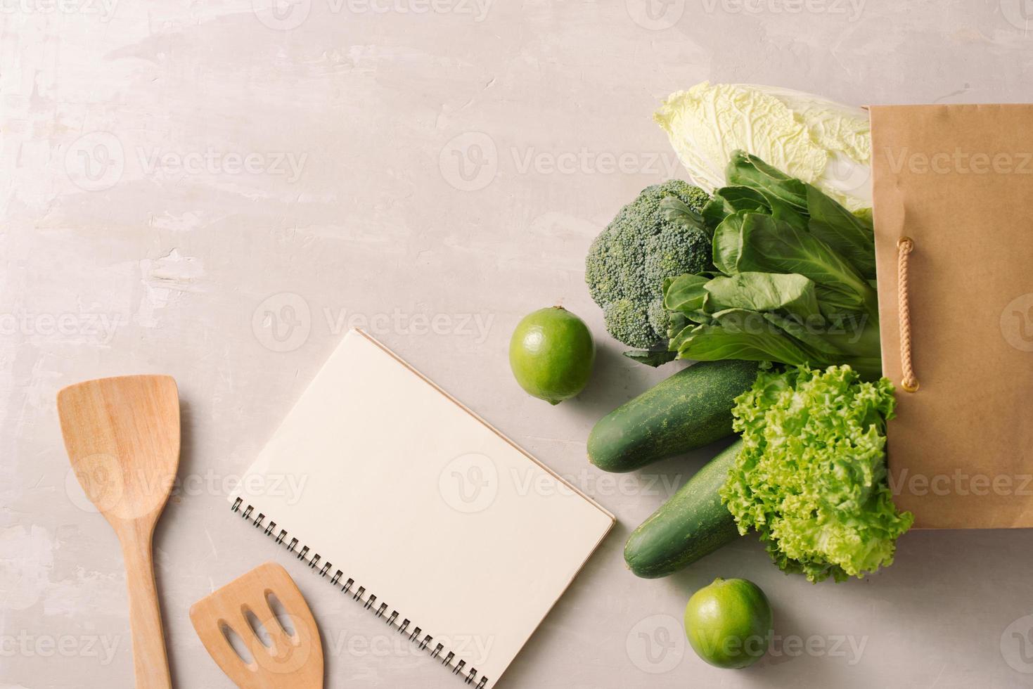 papper väska full av friska mat med anteckningsblock på en grå bakgrund. topp se. platt lägga foto