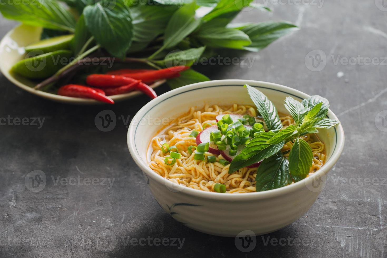 omedelbar spaghetti i skål med färsk örter, garnering av Koriander och asiatisk basilika, citron, kalk på mörk sten bakgrund foto