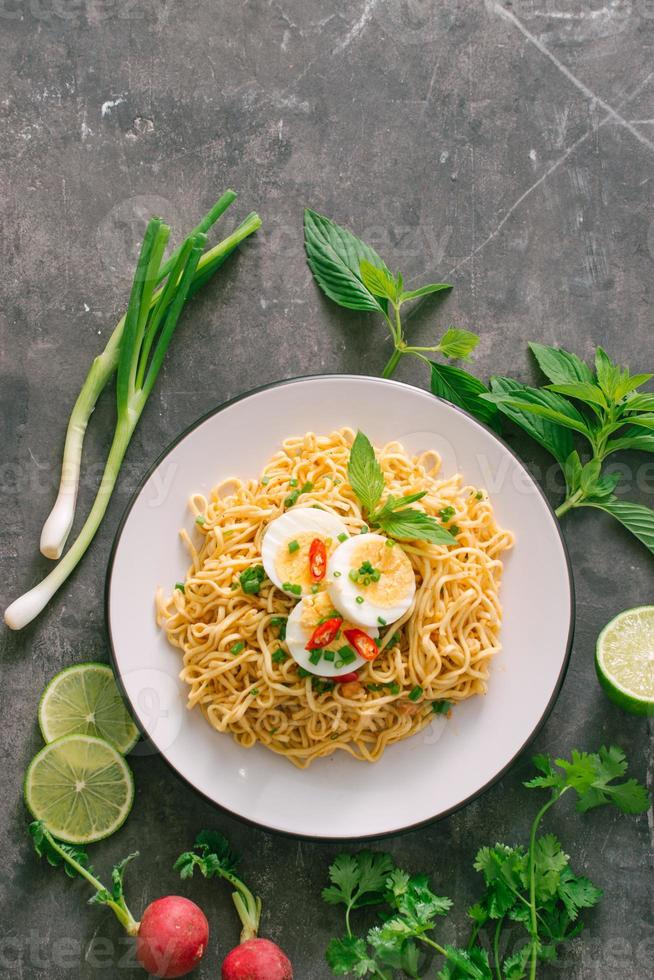 torr omedelbar spaghetti sätta ägg med färsk örter, garnering av Koriander och asiatisk basilika, citron, kalk på mörk sten bakgrund foto