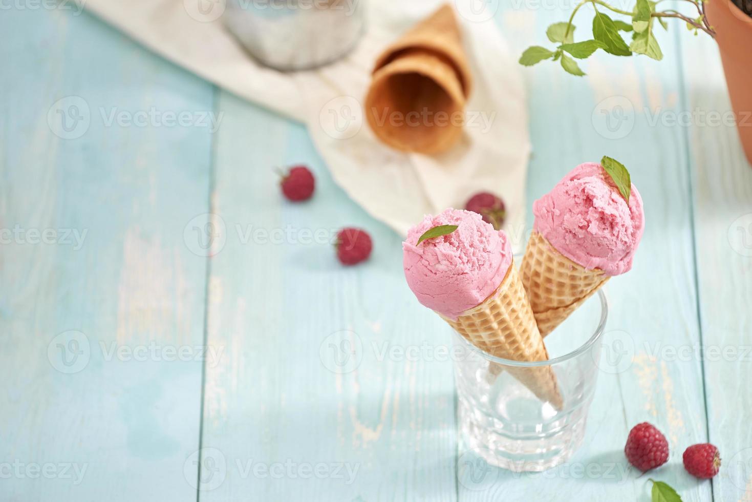 hemlagad hallon is grädde i våffla koner på rustik trä- bakgrund, selektiv fokus. sommar tid foto