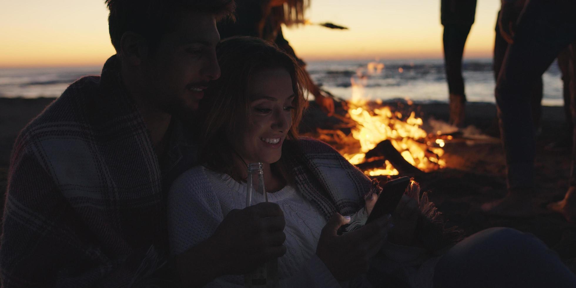 par njuter bål med vänner på strand foto