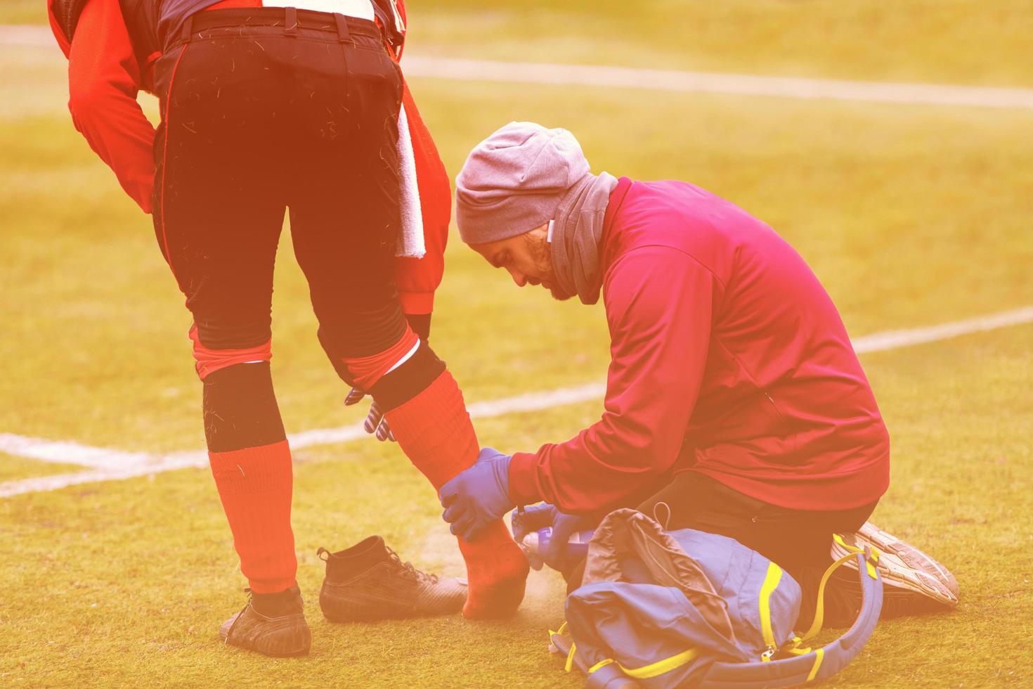 sporter läkare använder sig av frysning spray medan behandla skadade sportman foto