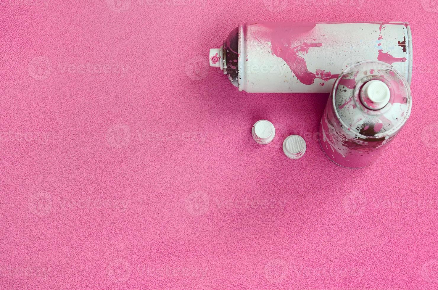 några Begagnade rosa aerosol spray burkar och munstycken med måla droppar lögner på en filt av mjuk och hårig ljus rosa skinna tyg. klassisk kvinna design Färg. graffiti huliganism begrepp foto