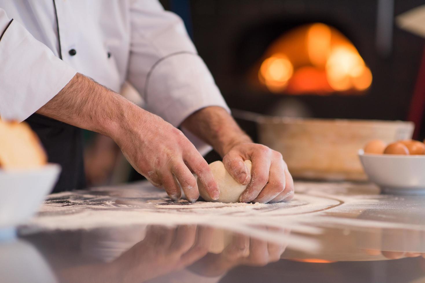 kock händer framställning deg för pizza foto