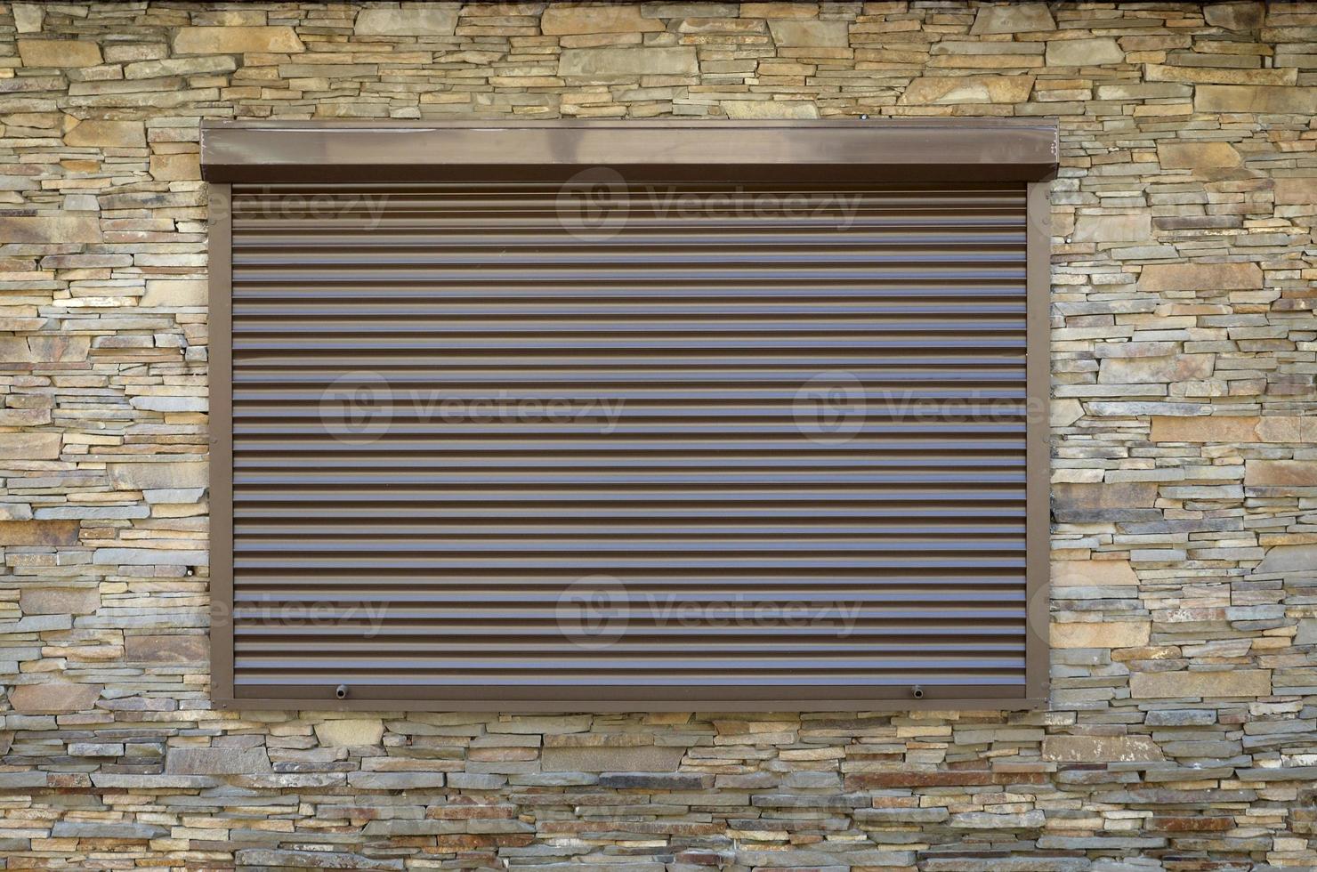 en fönster med brun metall rullande jalusier och vägg dekoration med artificiell sten foto