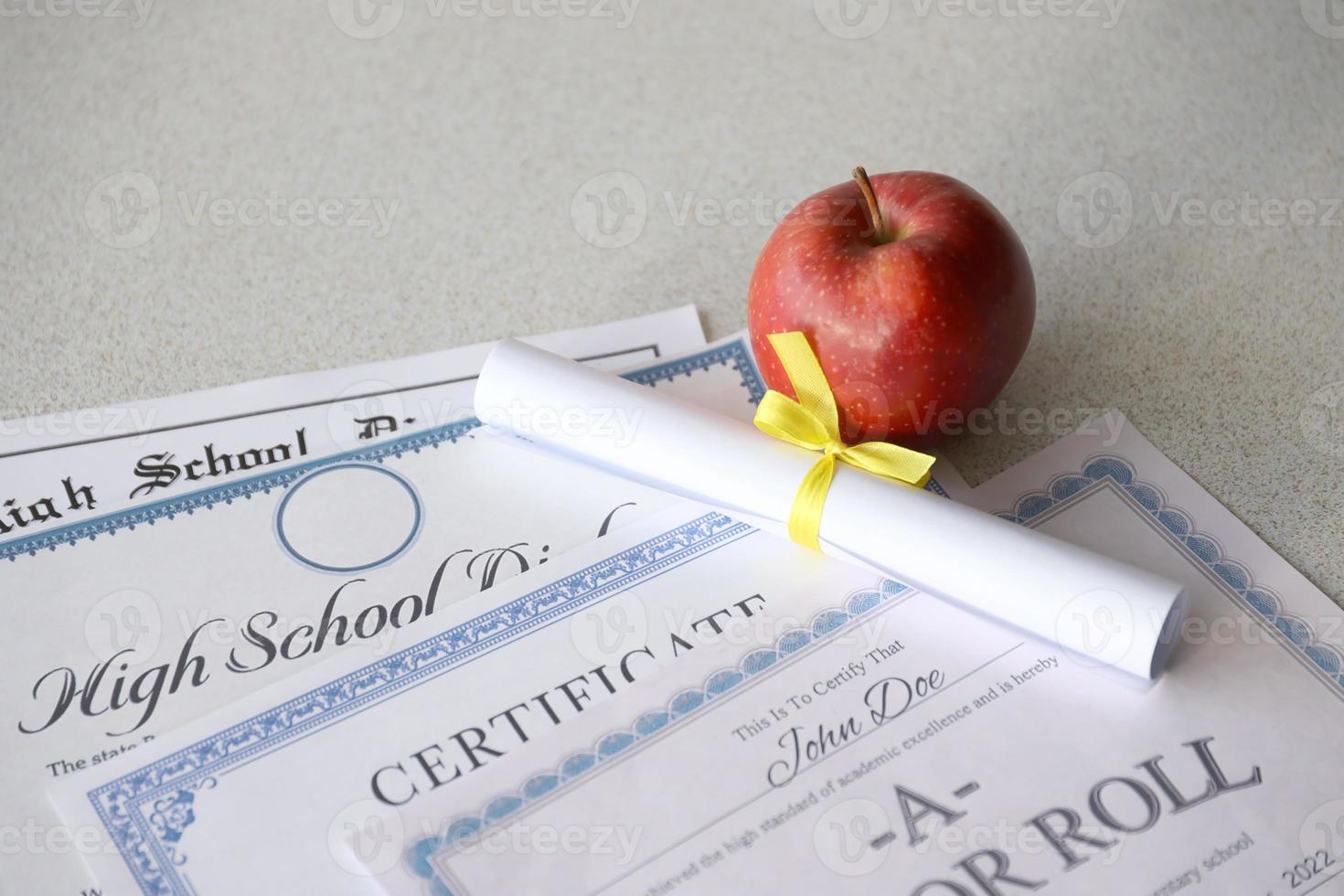 en hedra rulla erkännande, certifikat av prestation och hög skola diplom lögner på tabell med små skrolla och röd äpple. utbildning dokument foto