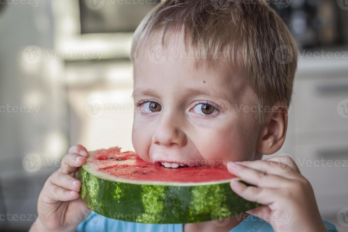 söt pojke äter vattenmelon på Hem. verklig känslor utan Framställ. foto