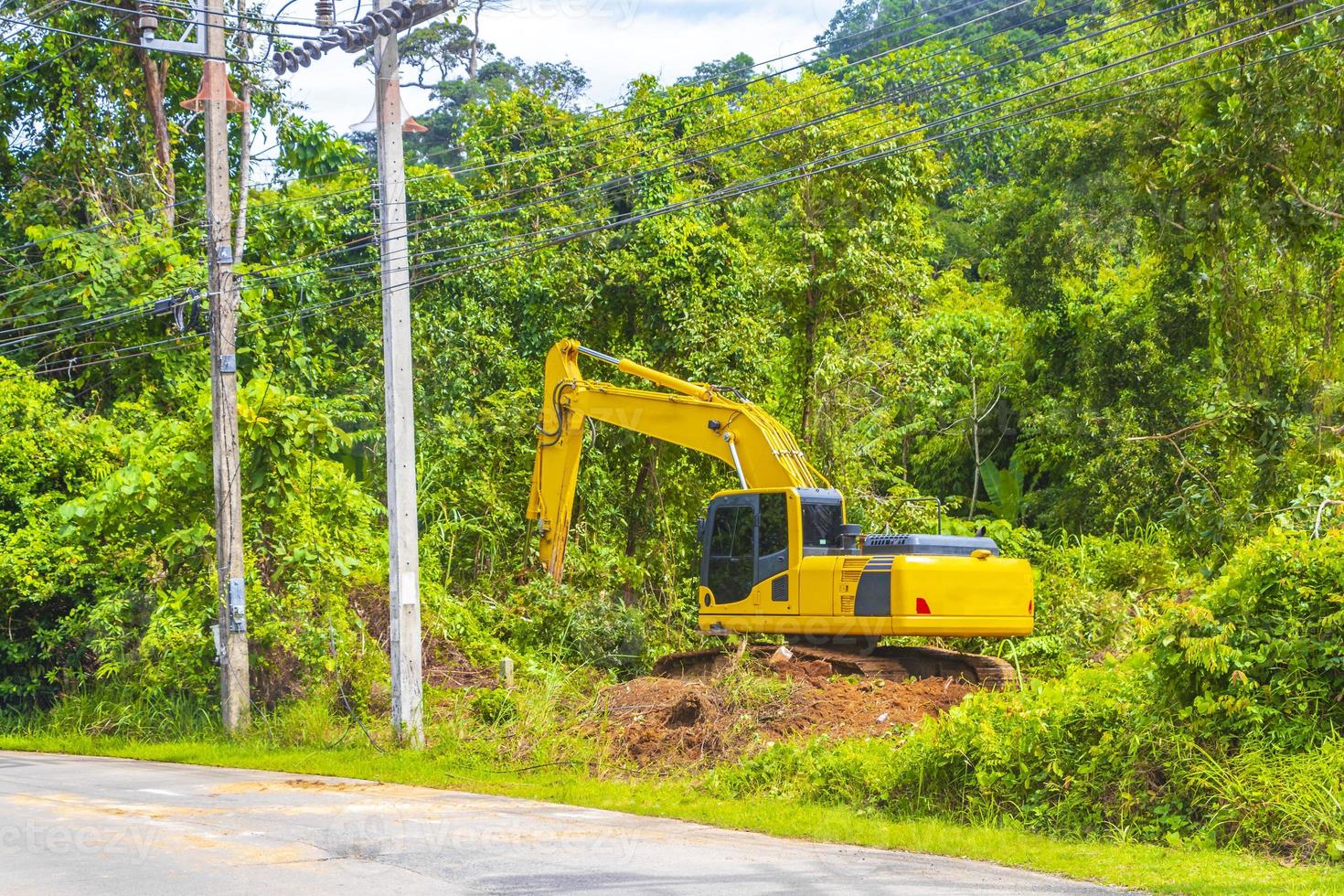 stor gul grävmaskin gräver förstör skog djungel på phuket thailand. foto