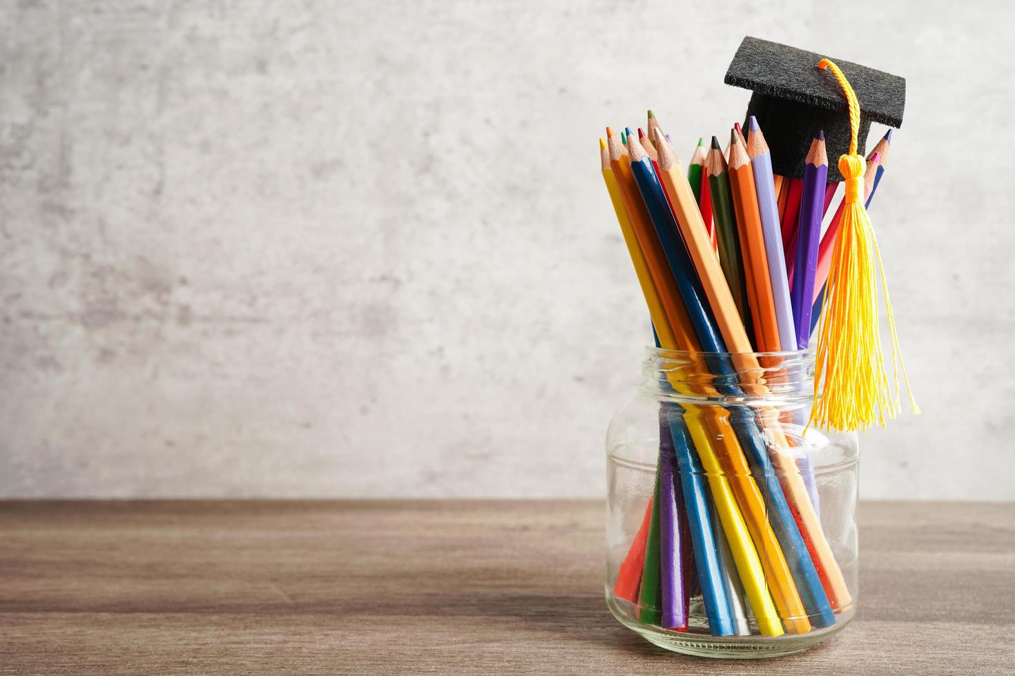 examen hatt med färgglada pennor på bok med kopia utrymme, lärande universitet utbildning koncept. foto