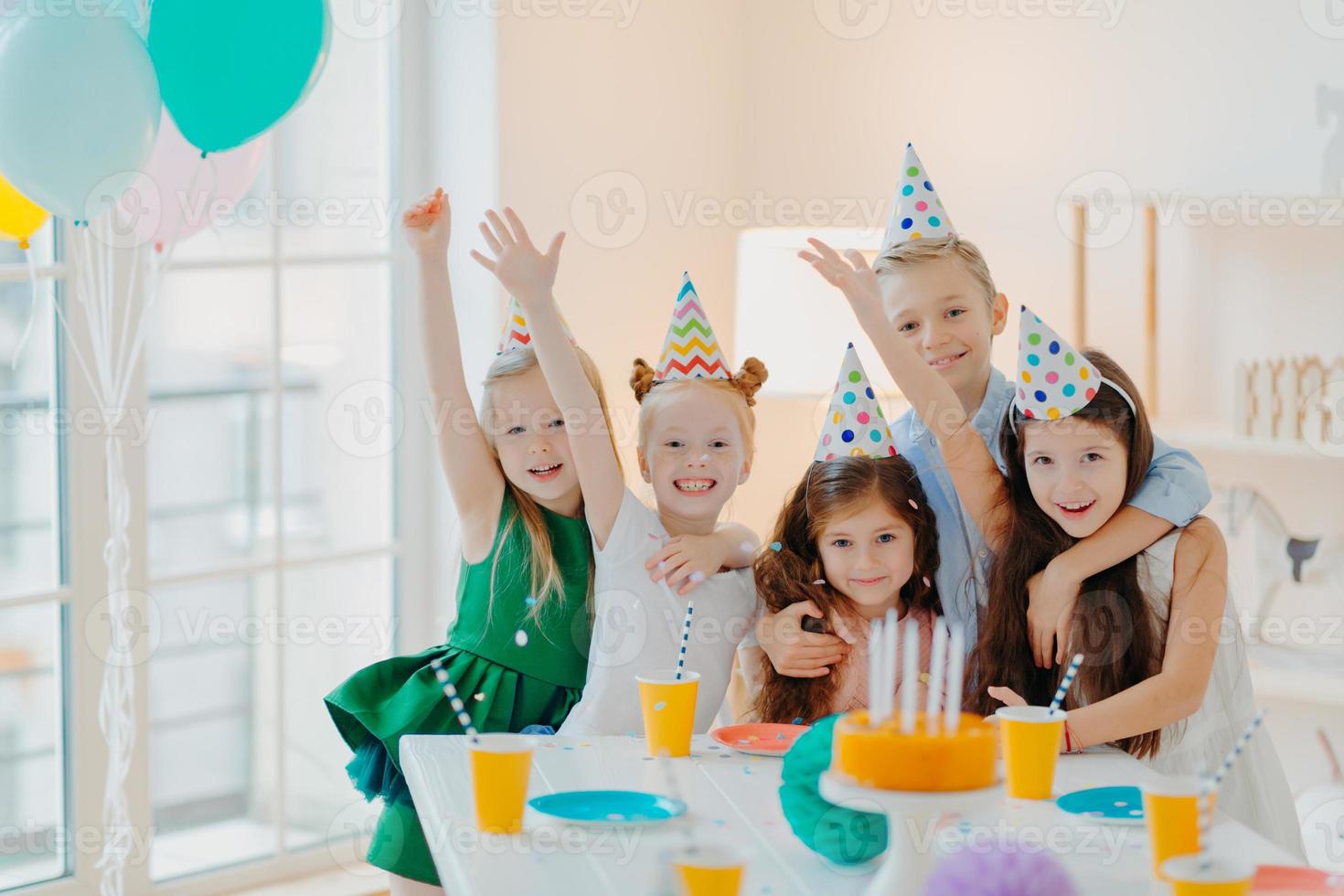 barnfest och firande koncept. grupp små barn vänner gör foto tillsammans, höjer armarna och ler glatt, har födelsedagsfest, festligt evenemang, dumt runt