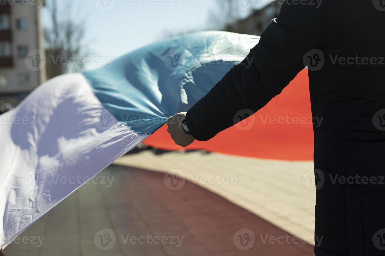 man innehar trasa. man innehar stor flagga av Ryssland. foto