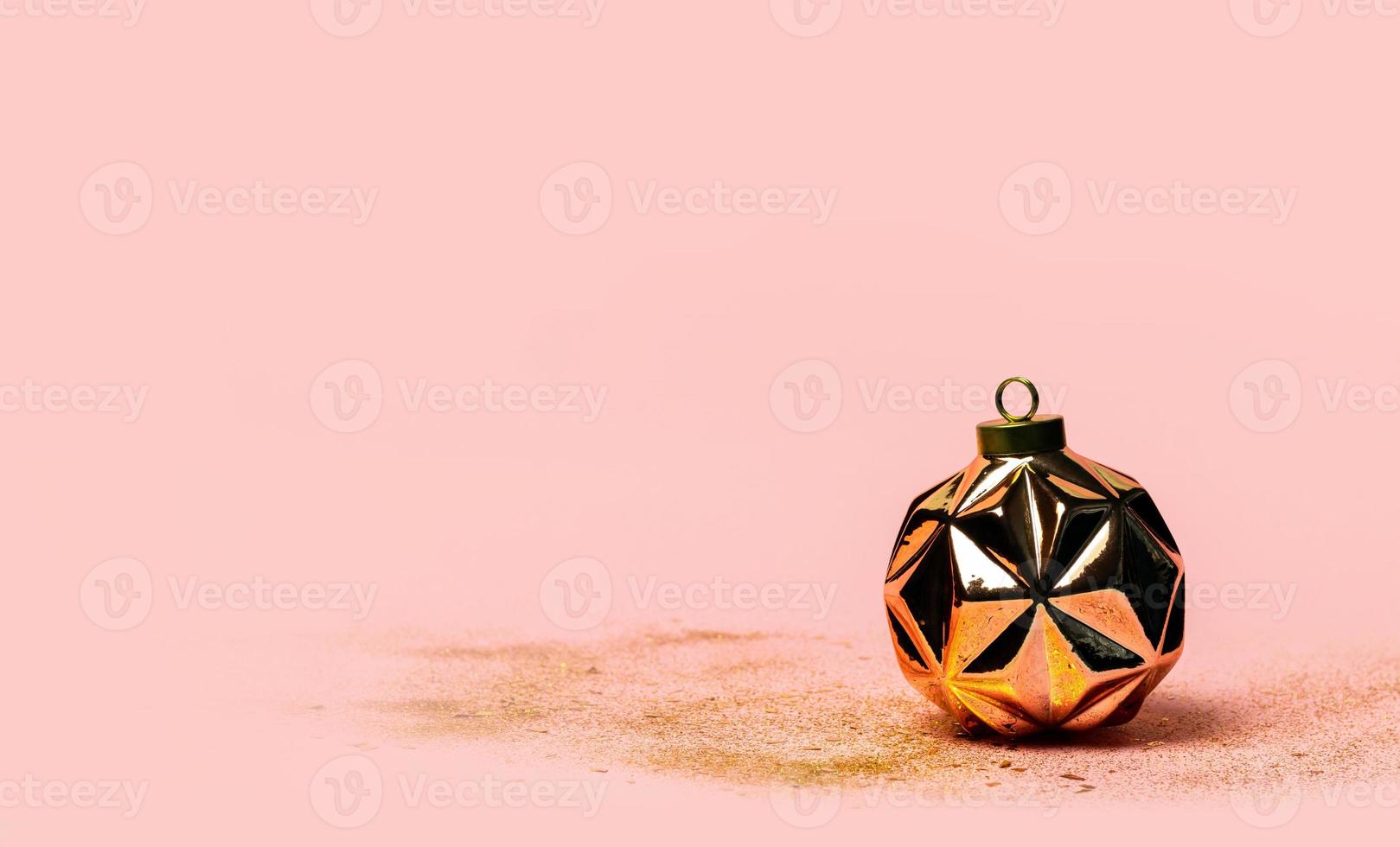 modern geometrisk reste sig guld jul boll eller prydnad och pärlar på rosa bakgrund. foto